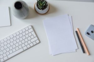 white printer paper beside white apple keyboard